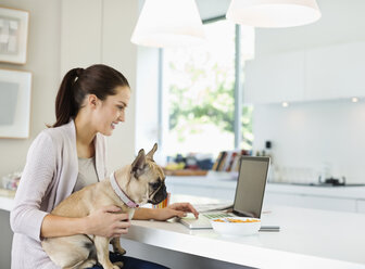 Frau mit Laptop und Hund auf dem Schoß - CAIF02221