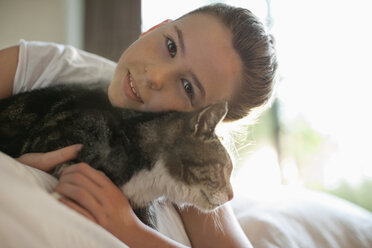 Girl petting cat on bed - CAIF02234