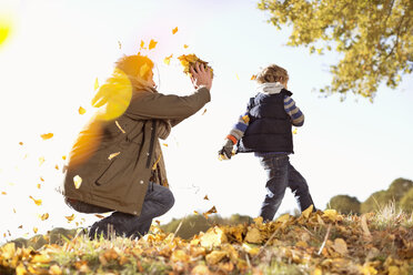 Vater und Sohn spielen im Herbstlaub - CAIF02276