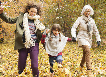 Three generations of women playing in autumn leaves - CAIF02281