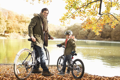 Vater und Sohn sitzen auf Fahrrädern im Park, lizenzfreies Stockfoto