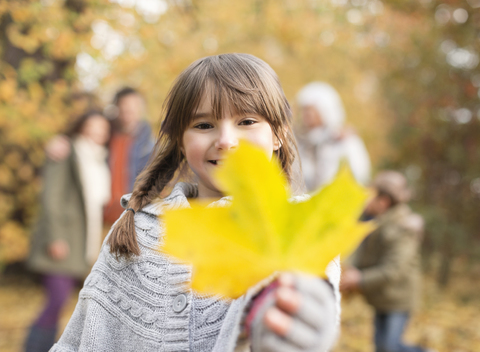 Mädchen hält Herbstblatt im Park, lizenzfreies Stockfoto