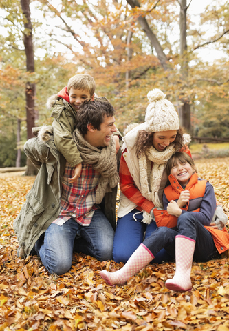 Familie spielt zusammen im Herbstlaub, lizenzfreies Stockfoto