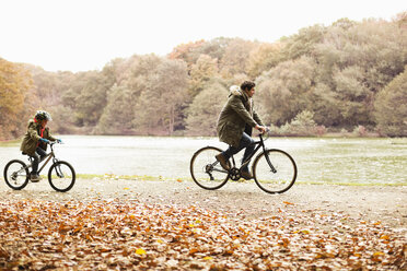 Vater und Sohn fahren mit dem Fahrrad im Park - CAIF02296