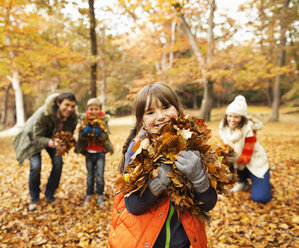 Family playing in autumn leaves - CAIF02312