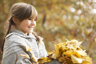 Smiling girl playing in autumn leaves - CAIF02314