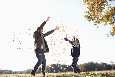 Vater und Sohn spielen im Herbstlaub - CAIF02336