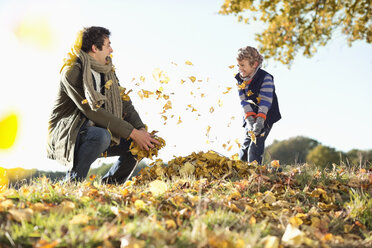 Vater und Sohn spielen im Herbstlaub - CAIF02339