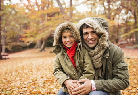 Vater und Sohn lächelnd im Park, lizenzfreies Stockfoto