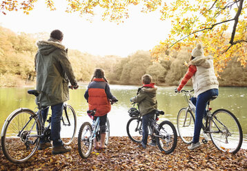 Familie sitzt zusammen im Park auf Fahrrädern - CAIF02345