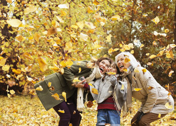 Three generations of women playing in autumn leaves - CAIF02349