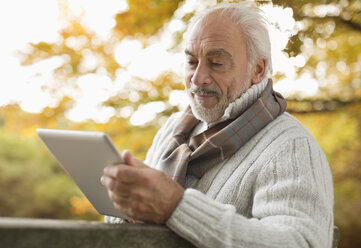 Älterer Mann benutzt Tablet-Computer im Park - CAIF02366