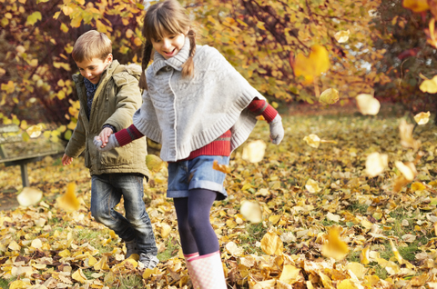 Kinder spielen im Herbstlaub, lizenzfreies Stockfoto