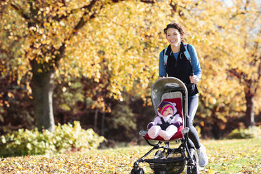 Frau läuft mit Kinderwagen im Park - CAIF02392