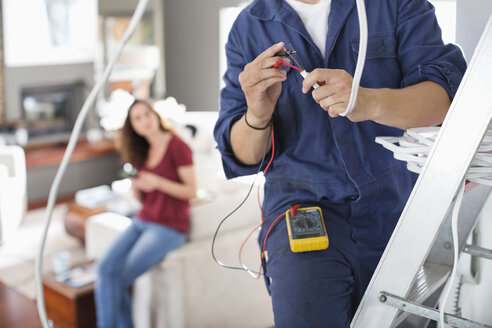 Elektriker bei der Arbeit im Wohnzimmer - CAIF02410