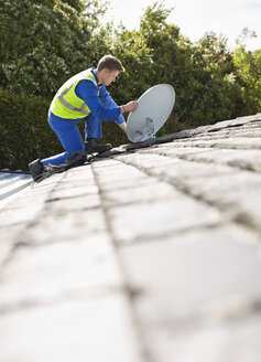 Arbeiter bei der Installation einer Satellitenschüssel auf dem Dach - CAIF02411