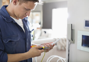 Elektriker bei Arbeiten am Telefon in der Wohnung - CAIF02423