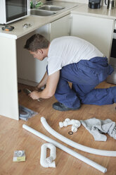 Klempner arbeitet an Rohren in der Küche - CAIF02427