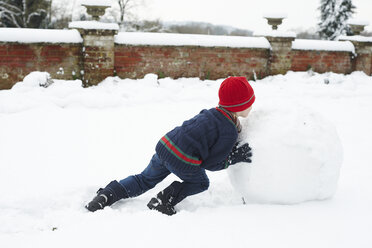 Junge baut Schneemann im Freien - CAIF02435