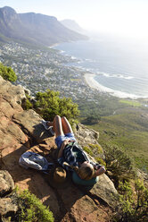 South Africa, Cape Town, woman lying on rock during hiking trip to Lion's Head - ECPF00229