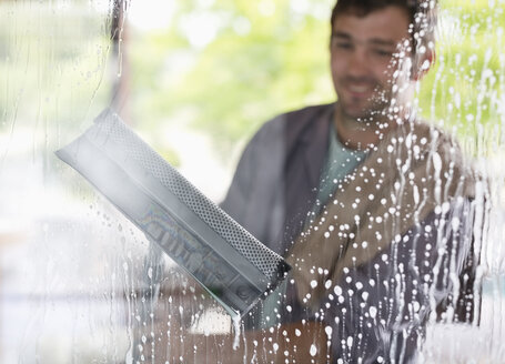 Mann wäscht Fenster mit Wischmopp - CAIF02526