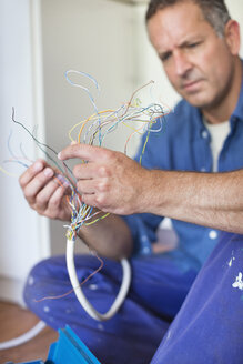 Elektriker bei der Prüfung von Kabeln in der Küche - CAIF02548