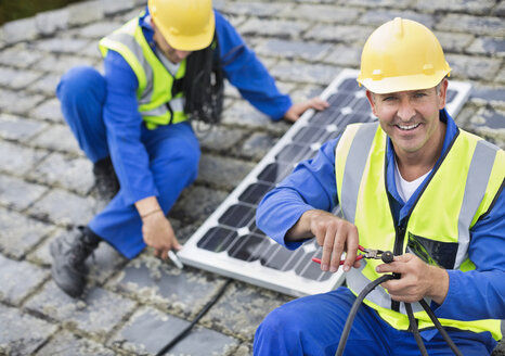 Arbeiter bei der Installation von Solarmodulen auf dem Dach - CAIF02550