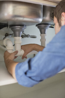 Klempner arbeitet an Rohren unter dem Waschbecken - CAIF02554