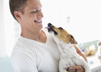 Smiling man holding dog - CAIF02557