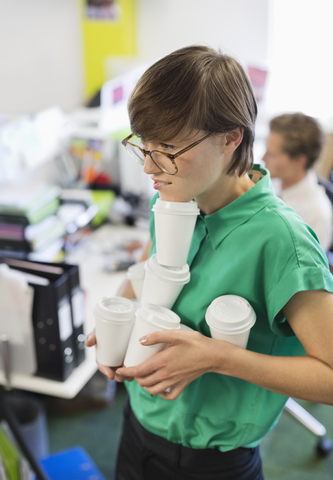 Geschäftsfrau balanciert Kaffeetassen im Büro, lizenzfreies Stockfoto