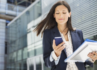 Geschäftsfrau benutzt Mobiltelefon im Büro - CAIF02637