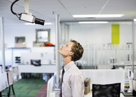 Businessman examining security camera in office - CAIF02640