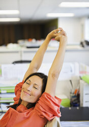 Businesswoman stretching at desk - CAIF02648