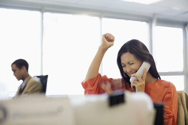 Businesswoman cheering at desk in office - CAIF02657