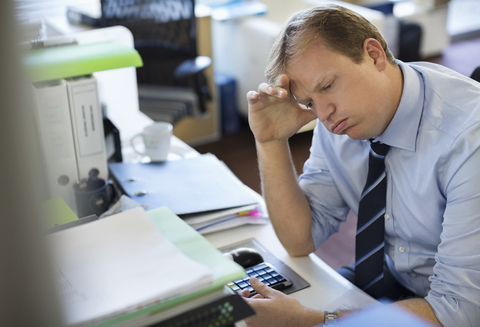 Geschäftsmann seufzt am Schreibtisch, lizenzfreies Stockfoto