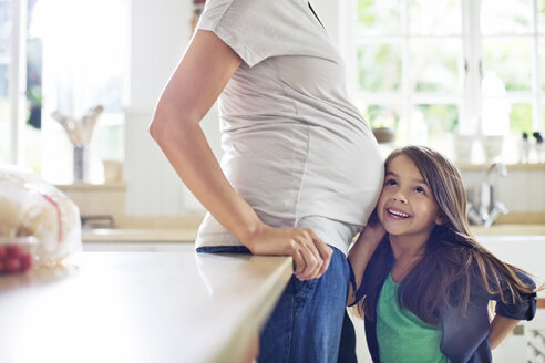 Mädchen lauscht dem Bauch der schwangeren Mutter - CAIF02674
