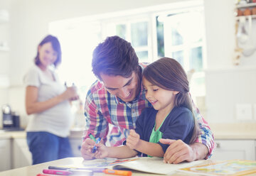 Father helping daughter use coloring book - CAIF02719