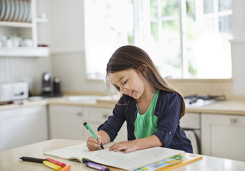 Girl using coloring book in kitchen - CAIF02720