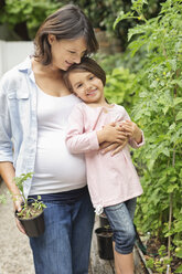 Schwangere Mutter und Tochter bei der gemeinsamen Gartenarbeit - CAIF02727