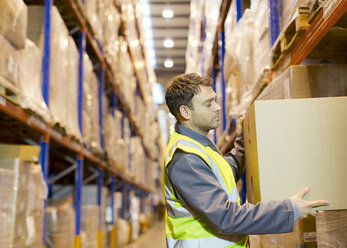 Worker stacking boxes in warehouse - CAIF02779