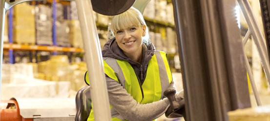 Worker operating forklift in warehouse - CAIF02784