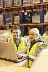 Workers using laptop in warehouse - CAIF02791
