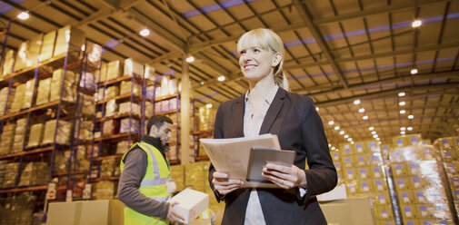 Businesswoman smiling in warehouse - CAIF02800