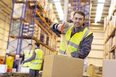 Worker taping cardboard box in warehouse - CAIF02820