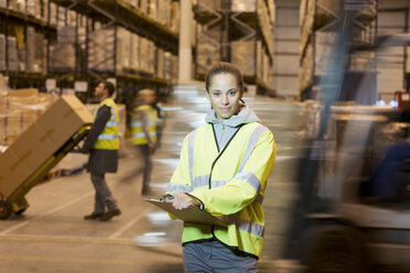 Worker holding clipboard in warehouse - CAIF02827