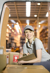 Delivery girl checking boxes in van - CAIF02853