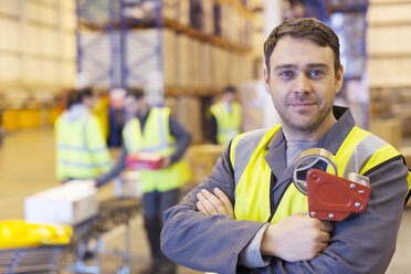 Worker holding tape dispenser in warehouse - CAIF02865