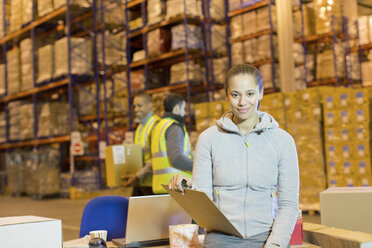 Worker holding clipboard in warehouse - CAIF02877