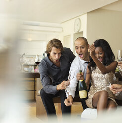 Freunde öffnen gemeinsam eine Flasche Champagner - CAIF02882