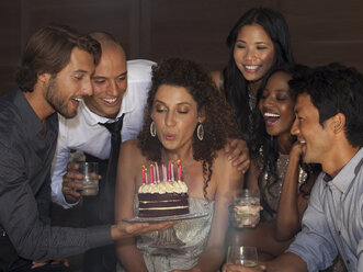 Woman blowing out birthday candles at party - CAIF02908